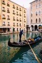 Venice, Italy - 04 october 2019: The gondolier rows a paddle in an empty gondola along the canal, against the backdrop