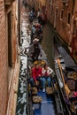 Venice, Italy - October 13, 2017: Tourists sail on a gondola on a narrow canal. The gondola is richly decorated with red