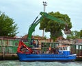 Self-propelled barge carrying an excavator and a tanker truck