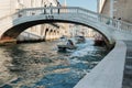A man and a woman float on a small boat under a bridge in Venice