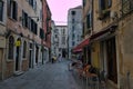 Venice, Italy: Small outdoor restaurant with red tables and chairs on narrow street - is one of the many bars Royalty Free Stock Photo