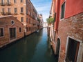 Venice, Italy - 17.10.2023: Small canal with boats and stunning old buildings, warm sunny day with blue cloudy sky. Sightseeing in