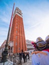 Venice, Italy - 17.10.2023: Stunning St Mark\'s Campanile and hats for tourists merchandise. Vertical image. Blue cloudy sky