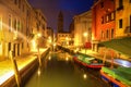 Venice at night, Italy. Beautiful view on narrow venetian canal with boats at night. Venezia illuminated by citylights Royalty Free Stock Photo