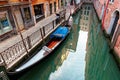 Venice on a peaceful morning, with view of an elegant gondola parking on a narrow canal, a tourist sitting by the quiet alley Royalty Free Stock Photo