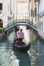 Venice street vertical cityscape. Small Rio De Lalboro canal with a forged bridge Sotoportego de le Ostreghe over it and gondolier