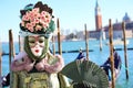 Venice, VE, Italy - February 13, 2024: masked woman with elegant green dress and Saint George bell tower in background