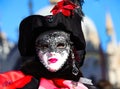 Venice, VE, Italy - February 13, 2024: masquerade woman with lipstick and white mask during the Venetian carnival
