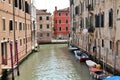 Venice water canal, typical Venetian architecture, boats parked by the canal, blue and red posts on the Venice canal, greenish wat Royalty Free Stock Photo