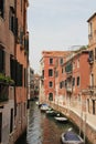 Venice water canal, typical Venetian architecture, boats parked by the canal, blue and red posts on the Venice canal, greenish wat Royalty Free Stock Photo