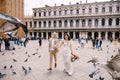 Venice Wedding, Italy. The bride and groom are running through a flock of flying pigeons in Piazza San Marco, amid the