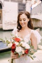 Venice wedding in Italy. A bride in a white dress, with a train, with a bouquet of white and red roses in her hands