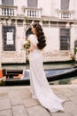 Venice wedding in Italy. A bride in a white dress, with a train, with a bouquet of white and red roses in her hands