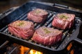 venison steaks on a cast iron griddle on a grill