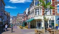 View on pedestrian shopping street with old traditional houses and cafe restaurants in dutch town in summer Royalty Free Stock Photo