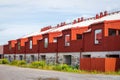 Perspective outdoor summer view of many red wooden buildings in a row.