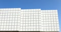 Ventilated facade cladding made of white squared alluminium tiles, in three separate walls.