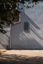 Ventilation grid casting shadows on concrete wall with rain gutter, urban detail Royalty Free Stock Photo