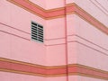 Ventilation grille mounted on pink wall of building.