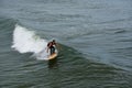 A lone male surfer wearing a wet suit concentrating on riding a wave