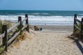 Ventnor, New Jersey - October, 2020: View along a sand path with a wooden fence towards an empty beach with one girl sunbather