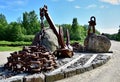 Two monuments of large rusty anchors with a chain and boulders