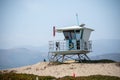 A lifeguard at Ventura Harbor watches from inside a lifeguard tower at a breakwater