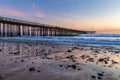 Ventura Pier at Sunset. Beach with rocks in foreground, smooth ocean; colored sky in background. Royalty Free Stock Photo