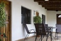 Veranda with chairs and table on the wooden floor. Front facade with door and windows and plants