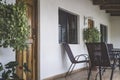 Veranda with chairs and table on the wooden floor. Front facade with door and windows and plants Royalty Free Stock Photo