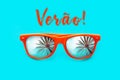 Verao text in Portuguese: Summer and orange sunglasses with palm tree reflections isolated in cyan background. Royalty Free Stock Photo