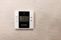 Verdant brand thermostat on a wallpapered wall