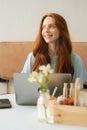 Verical medium shot portrait of smiling young woman working typing using on laptop computer sitting at table in cozy Royalty Free Stock Photo