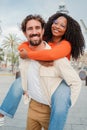 Verical portrait of couple embracing and having fun. Man giving his african american girlfriend a romantic piggyback Royalty Free Stock Photo