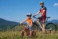 Verkhovyna, Ukraine - August 19, 2017: Tourist bikers, dad and small boy on mountain bicycles in high grass