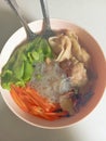 Vermicelli soup with toppings of carrots, lettuce, mushrooms and dumplings taken from above and a bit far