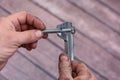 Vernier caliper and screw-bolt. Rough smeared working men& x27;s hands.