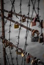 Vertical shot of padlocks locked on a metal gate with barbed wire and messages of love on the locks Royalty Free Stock Photo