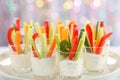 Verrines appetizer with carrot, cucumber, celery and red bell pepper sticks in glasses on platter at bokeh background,