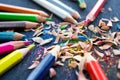 Versicolored pencils with knot of wooden shavings on black background