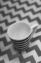 Verti grayscale shot of a mug with a striped pattern on a zigzag background Royalty Free Stock Photo