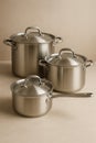 Three stainless steel pots of varying sizes with lids, arranged on a neutral surface. Royalty Free Stock Photo