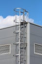 Vertical access ladders with round safety tunnel for use as emergency fire escape on side of new industrial building