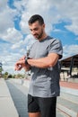 Vertical. Active Young Energetic Sports Man Checking His Progress on Smart Watch Gear During Outdoor Running Workout Royalty Free Stock Photo