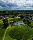 Vertical aerial view from behind of Jelling Mounds, Runic Stones, and Church under the cloudy sky