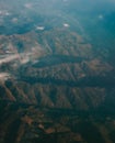Vertical aerial shot of rugged green mountain ridges and valleys partially covered by morning mist Royalty Free Stock Photo