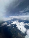 Vertical aerial view of a rural landscape enveloped in puffy clouds in blue sky background Royalty Free Stock Photo