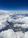 Vertical aerial view of a rural landscape enveloped in puffy clouds in blue sky background Royalty Free Stock Photo