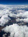 Vertical aerial view of a rural landscape enveloped in puffy clouds in blue sky background Royalty Free Stock Photo