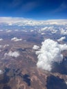 Vertical aerial view of a rural landscape enveloped in puffy clouds in blue sky background Royalty Free Stock Photo